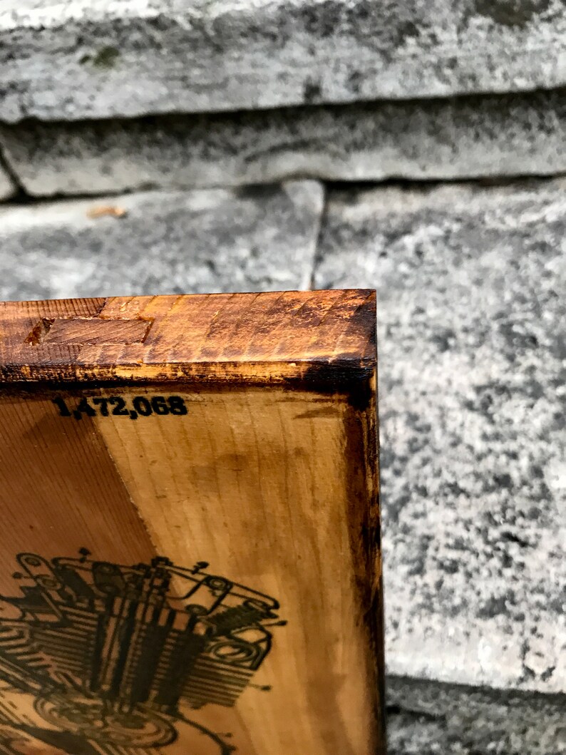 Puede incluir: Un letrero de madera con una ilustraci&oacute;n en blanco y negro de un motor de motocicleta. El letrero tiene una mancha marr&oacute;n y el n&uacute;mero 1.472.068 est&aacute; impreso en la parte superior.
