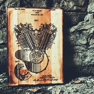 Puede incluir: Un letrero de madera vintage con una ilustraci&oacute;n en blanco y negro de un motor de motocicleta. El letrero tiene el texto "Oct. 30, 1923. W.S. Harley. Filed April 20, 1920. 1,412,068." impreso en &eacute;l.