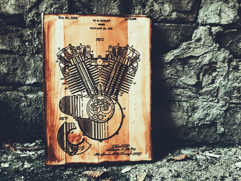 Puede incluir: Un letrero de madera vintage con una ilustraci&oacute;n en blanco y negro de un motor de motocicleta. El letrero tiene el texto "Oct. 30, 1923. W.S. Harley. Filed April 20, 1920. 1,412,068." impreso en &eacute;l.
