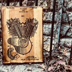 Puede incluir: Una placa de madera con un dibujo en blanco y negro de un motor Harley Davidson patentado. El n&uacute;mero de patente es 1.412.068 y la fecha es el 30 de octubre de 1923. El texto "W. S. Harley, Inventor" est&aacute; en la parte inferior de la placa.