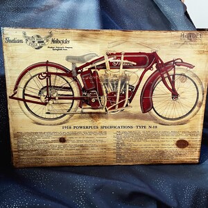 May include: A vintage wood sign with a red and black illustration of a 1918 Indian Motorcycle, labeled "Powerplus Specifications - Type N-18". The sign features the text "World's Most Copied Motorcycle" and "Indian Motorcycle Company Springfield, Mass."