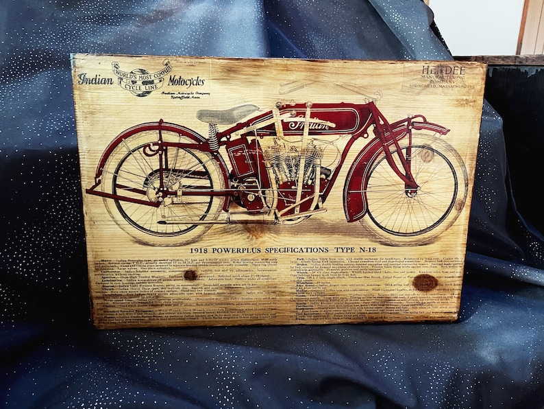 May include: A vintage wood sign with a red and black illustration of a 1918 Indian Motorcycle, labeled "Powerplus Specifications - Type N-18". The sign features the text "World's Most Copied Motorcycle" and "Indian Motorcycle Company Springfield, Mass."