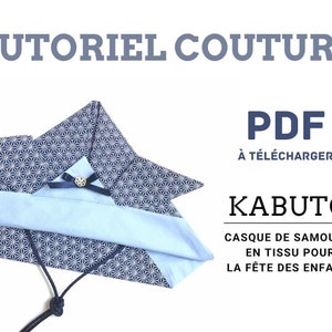 May include: A blue and white patterned fabric helmet with a black cord. The helmet is folded and has a small blue bow on the front. The text "TUTORIEL COUTURE PDF À TÉLÉCHARGER KABUTO CASQUE DE SAMOURAÏ EN TISSU POUR LA FÊTE DES ENFANTS" is written in black on a white background.