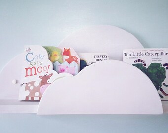 May include: White cloud-shaped bookshelf with rounded edges, holding a variety of children's books, including "Cow Says Moo!" and "Ten Little Caterpillars".
