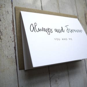 May include: White card with black calligraphy that reads "Always and Forever You and Me".
