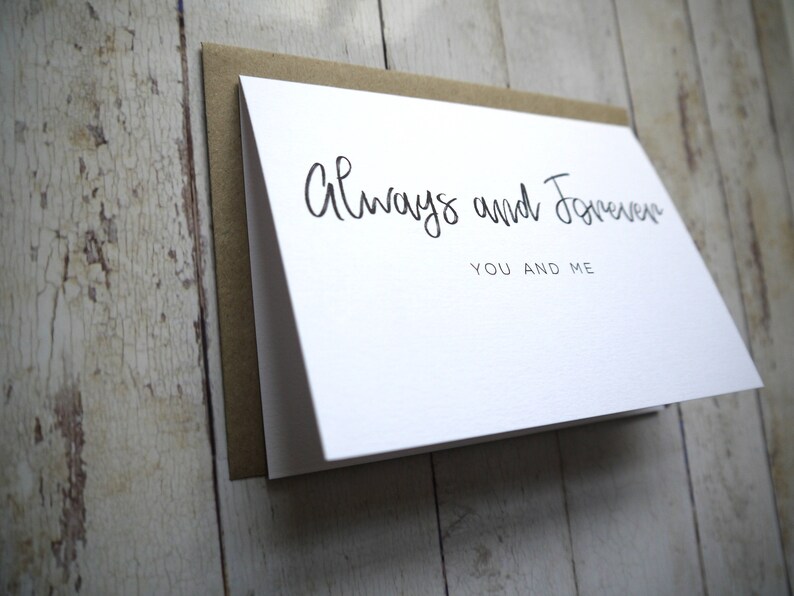 May include: White card with black calligraphy that reads "Always and Forever You and Me".
