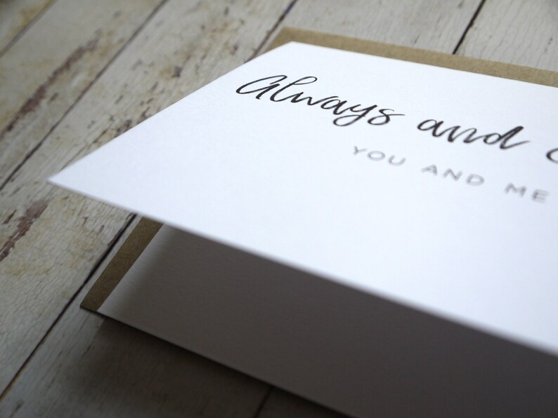 May include: A white card with the text "Always and forever, you and me" written in black cursive script.