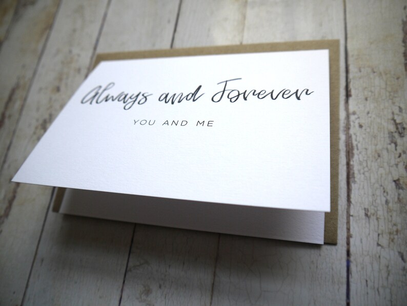 May include: A white card with brown paper backing. The card has black calligraphy that reads "Always and Forever" with the words "You and Me" underneath.