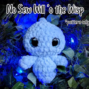 Peut inclure: Un jouet en peluche crocheté bleu clair avec de grands yeux noirs, présentant le texte No Sew Will 'o the Wisp et *pattern only* en lettres blanches sur un fond sombre avec du feuillage vert et des lumières bleues.