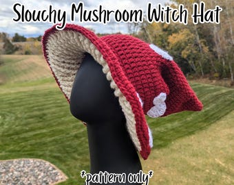 Op de afbeelding: Een slappe paddenstoel heksenhoed met een donkerrode buitenkant, witte gehaakte stippen en een crèmekleurige onderkant. De tekst Slouchy Mushroom Witch Hat en *pattern only* is zichtbaar. Dit gehaakte hoofddeksel heeft een brede, slappe rand.