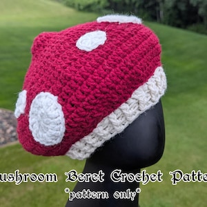 May include: A handmade crochet mushroom beret in a vibrant red with white spots and a cream-colored brim. The hat is designed to resemble a mushroom. The text on the image reads "Mushroom Beret Crochet Pattern *pattern only*".