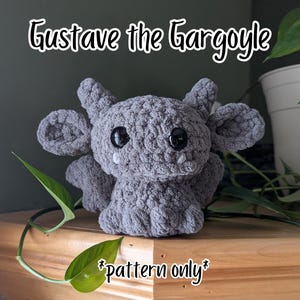 May include: A gray crocheted gargoyle plush toy with large black eyes, small horns, and large ears. The text "Gustave the Gargoyle" is above the plush toy, and "pattern only" is below it.