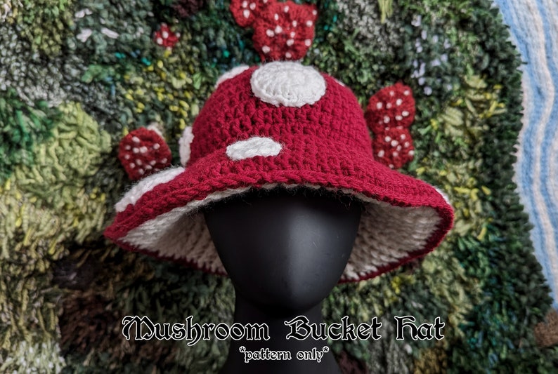 May include: A red and white crocheted mushroom bucket hat with white polka dots. The hat is on a mannequin head and the background is a green and brown rug.