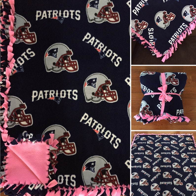 May include: A navy blue fleece blanket with a pink knotted fringe. The blanket features a repeated pattern of a football helmet with the word "Patriots" printed on it.
