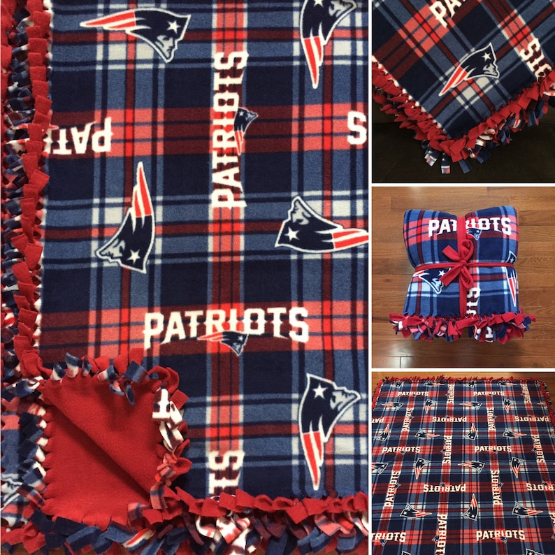 May include: A red and blue plaid fleece blanket with the New England Patriots logo and the word "Patriots" repeated throughout. The blanket is tied with a red ribbon.
