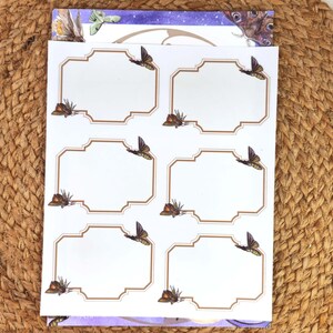 May include: A sheet of white labels with a brown border and butterfly illustrations. Each label has a blank space for text. The labels are stacked on top of a purple and white patterned sheet.