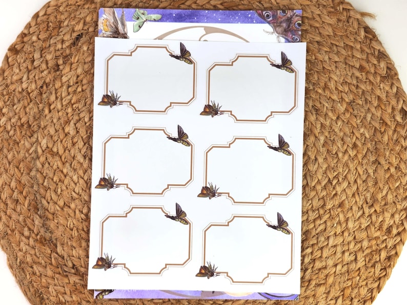 May include: A sheet of white labels with a brown border and butterfly illustrations. Each label has a blank space for text. The labels are stacked on top of a purple and white patterned sheet.