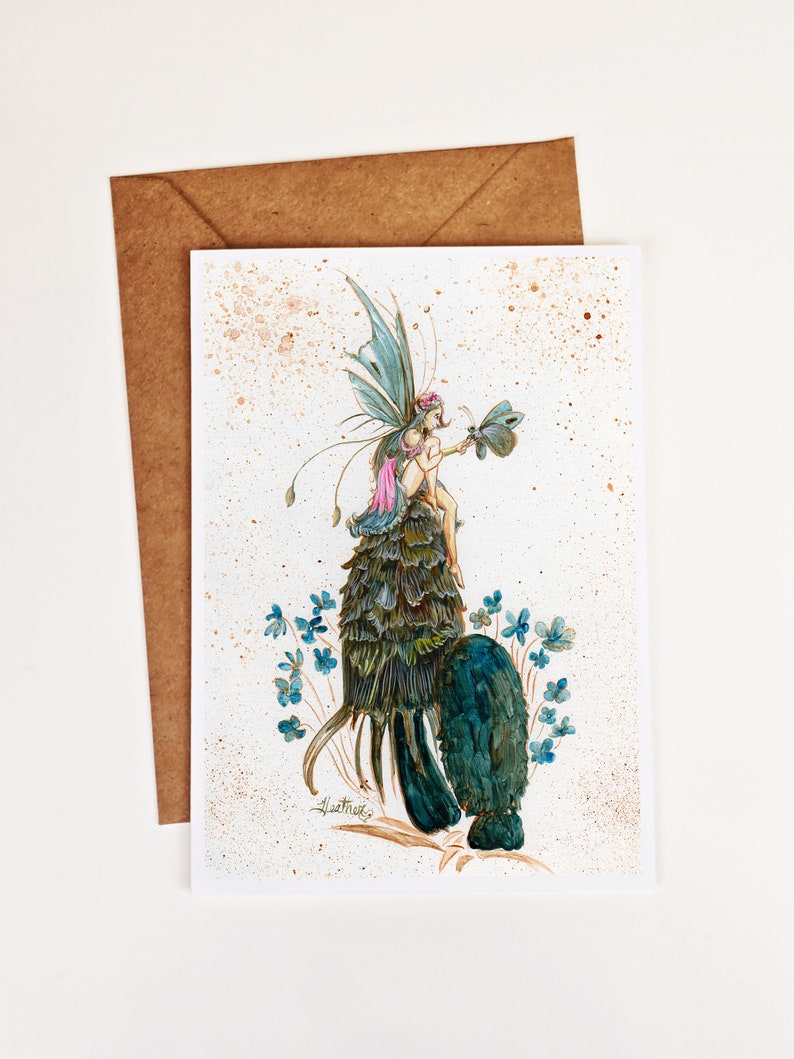 May include: A watercolor painting of a fairy with blue wings and a pink dress riding on a large mushroom. The fairy is holding a butterfly in her hand. The background is a light brown with white speckles.