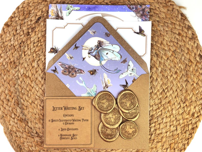 May include: A letter writing set featuring illustrated paper and envelopes with a moth and butterfly theme. The set includes six gold-colored wax seals. The set is displayed on a woven, tan surface.