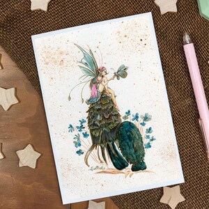 May include: A watercolor painting of a fairy sitting on a green and blue leafy creature. The fairy has pink wings and is holding a small butterfly. The background is a light brown with white speckles.