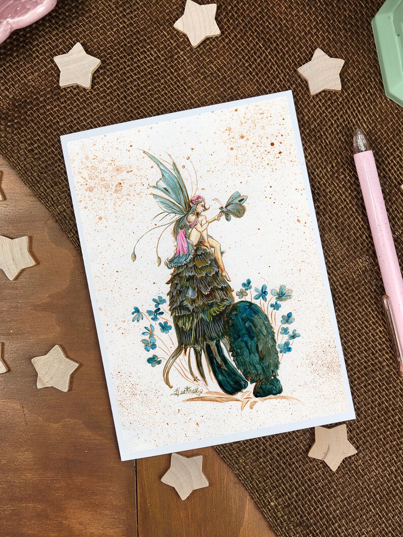 May include: A watercolor painting of a fairy sitting on a green and blue leafy creature. The fairy has pink wings and is holding a small butterfly. The background is a light brown with white speckles.
