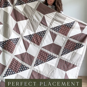 May include: A quilt kit with a geometric pattern in shades of brown, white, and black. The quilt is made of fabric with a variety of textures and patterns. The text "PERFECT PLACEMENT QUILT PATTERN QUILT KIT WWW.SEWNHANDMADE.COM" is printed on the bottom of the image.