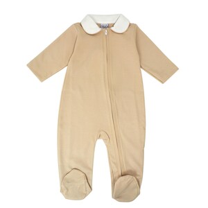 May include: Tan baby sleeper with a white collar and a full-length zipper. The sleeper has long sleeves and attached feet. The collar is trimmed with a light tan color. The sleeper is made of a soft material.