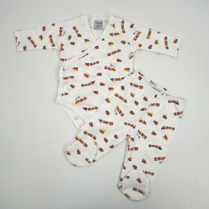 May include: A white long-sleeve wrap-style bodysuit and matching footed pants set featuring a repeating pattern of small red, yellow, and blue steam trains. The bodysuit has a V-neckline and snap closures, while the pants have an elastic waistband.
