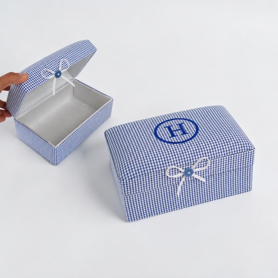 Fabric-wrapped baby memory box in classic seersucker check with personalized monogram — 418 favorites signal this is genuinely beloved, and the textile approach sets it apart from every other wooden box.