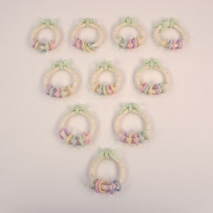 Puede incluir: Doce coronas de color pastel con lunares verdes y un lazo. Cada corona tiene un juego de anillos de color pastel colgando.