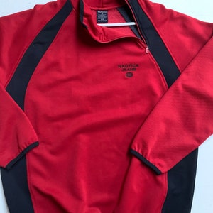 Puede incluir: Sudadera roja de cremallera de un cuarto con ribetes negros y el logotipo de Nautica Jeans en la parte delantera.