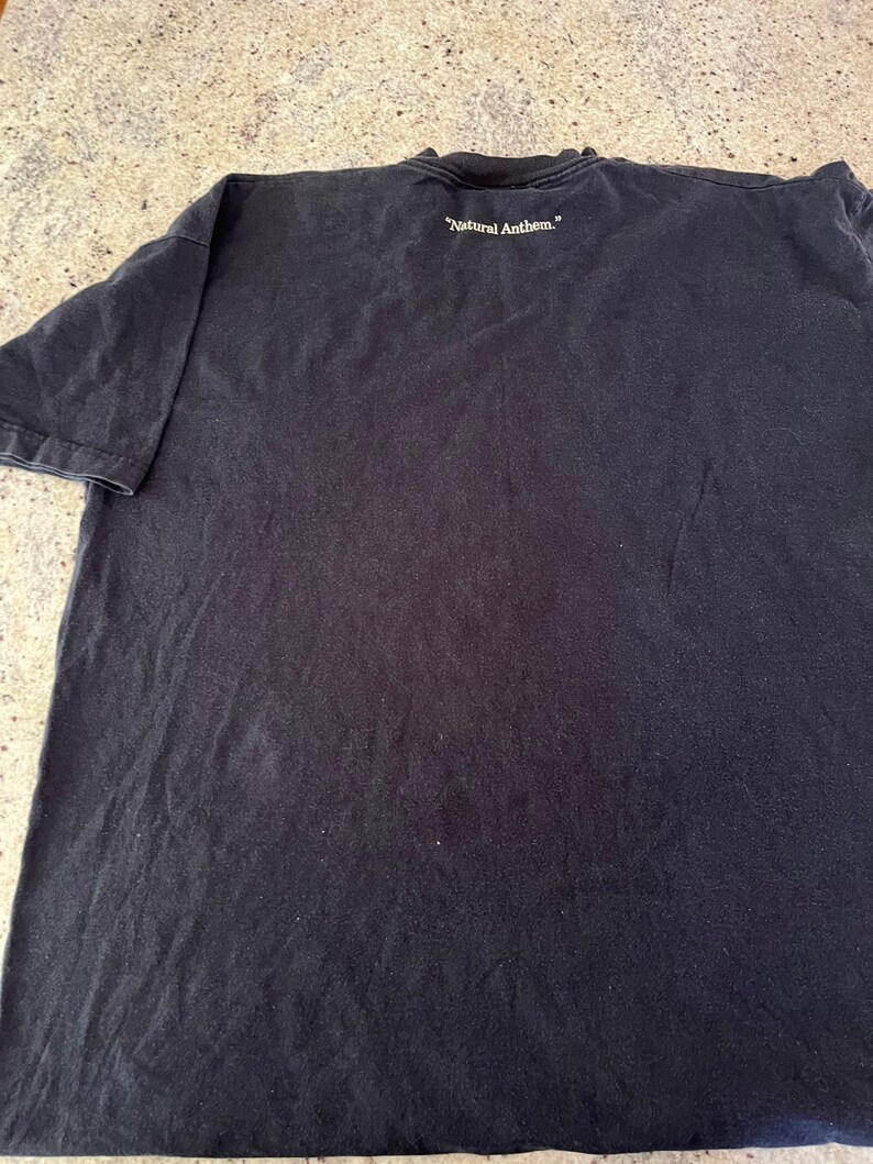 Puede incluir: Camiseta negra con el texto "Natural Anthem." impreso en la espalda.