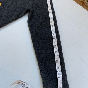 May include: Gray fleece zip-up jacket with a Mickey Mouse graphic and the word "Mickey" embroidered on the front. The jacket has a zipper closure and a stand-up collar. The sleeve length is 18 inches.