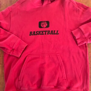 May include: Red hooded sweatshirt with a black basketball graphic and the word "BASKETBALL" printed on the front.