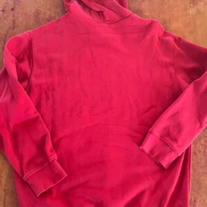 May include: A red hooded sweatshirt with a pouch pocket.