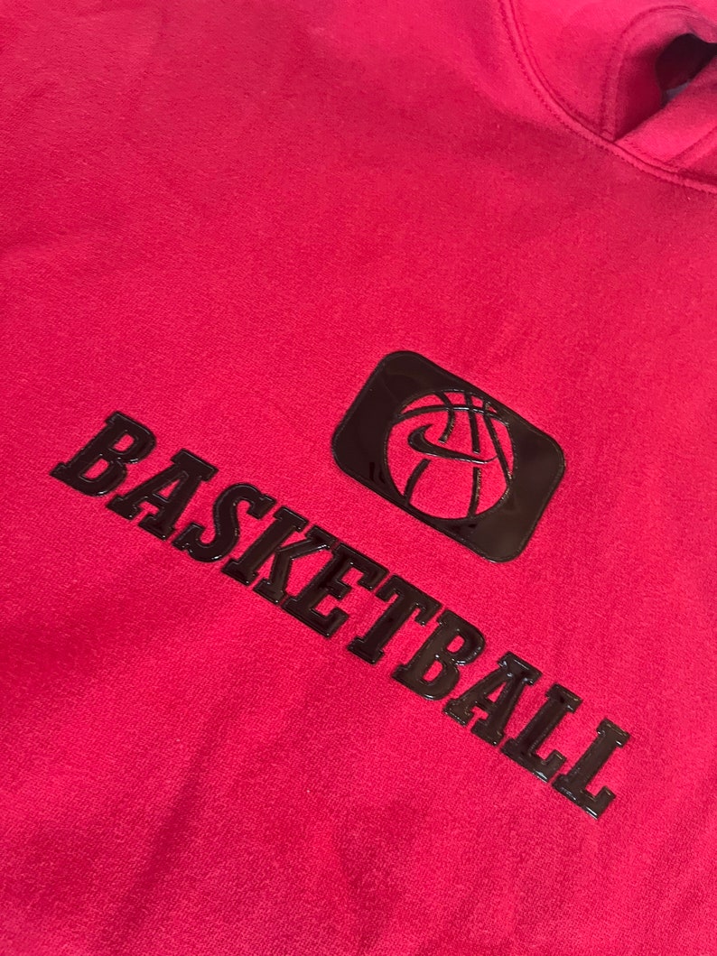 May include: Red hooded sweatshirt with a black basketball graphic and the word "BASKETBALL" in black lettering.
