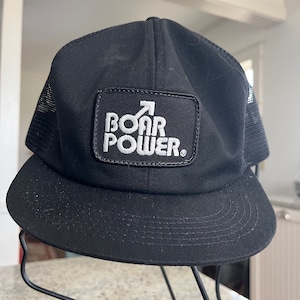 May include: Black trucker hat with a white patch that says "BOAR POWER" with an arrow pointing up.