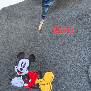 May include: Gray fleece zip-up hoodie with a Mickey Mouse graphic and the word "MICKEY" embroidered in red.