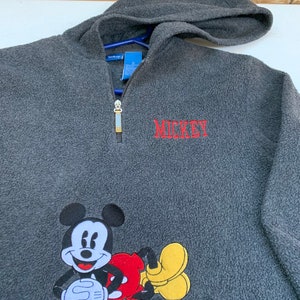 May include: A gray fleece pullover hoodie with a red embroidered Mickey Mouse design and the word "MICKEY" in red embroidery.