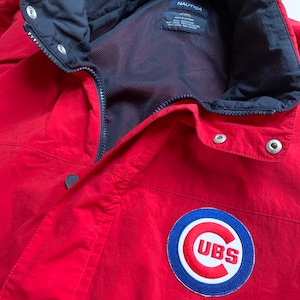May include: Red Nautica jacket with a Chicago Cubs logo patch. The jacket has a black zipper and a mesh lining. The tag says "Nautica" and "XXL".