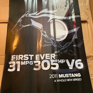 May include: A black and white poster advertising the 2011 Ford Mustang. The poster features a stylized image of a Mustang horse, a speedometer, and the text "First Ever 31 MPG 305 HP V6 2011 Mustang A Whole New Breed".