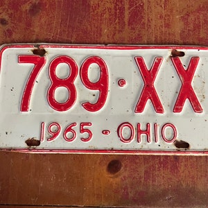 May include: A white and red vintage Ohio license plate with the number 789-XX and the year 1965.