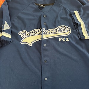 May include: A navy blue baseball jersey with white and gray trim. The front of the jersey features the text "The Kwon Do" in white with a white and gray swoosh design. The text "태권도" is also embroidered on the jersey in white.