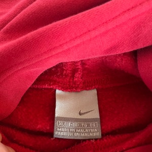 May include: A red Nike hoodie with a white tag that reads "XL (43-45) TG EG" and "MADE IN MALAYSIA FABRIQUE EN MALAISIE".