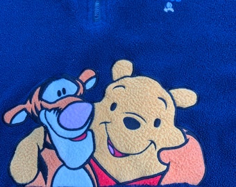 May include: Blue fleece pullover with a Winnie the Pooh and Tigger applique. The pullover has a zipper and the text "100 ACRE WOOD" is embroidered on the front.