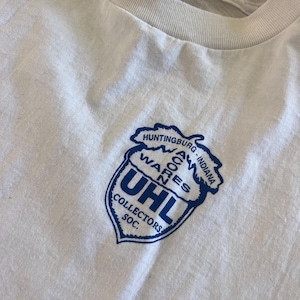May include: White t-shirt with a blue and white logo that says "UHL Collectors Soc." and "Huntingburg, Indiana - Wares Acres" in a blue acorn shape.