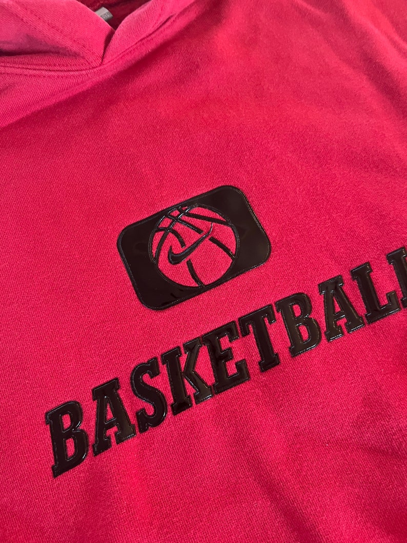 May include: A red hoodie with a black basketball graphic and the word "BASKETBALL" in black lettering.