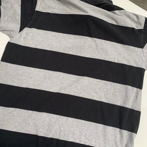May include: A black and gray striped polo shirt. The shirt has a classic collar and short sleeves.