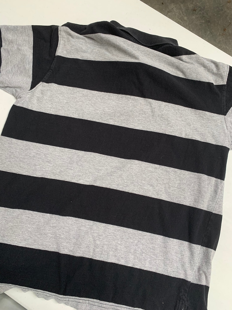May include: A black and gray striped polo shirt. The shirt has a classic collar and short sleeves.