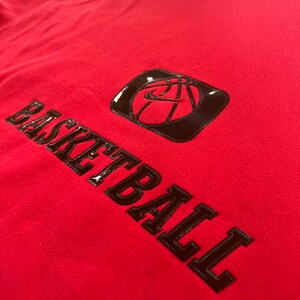 May include: Red hoodie with a black basketball graphic and the word "BASKETBALL" in large, bold, black letters.